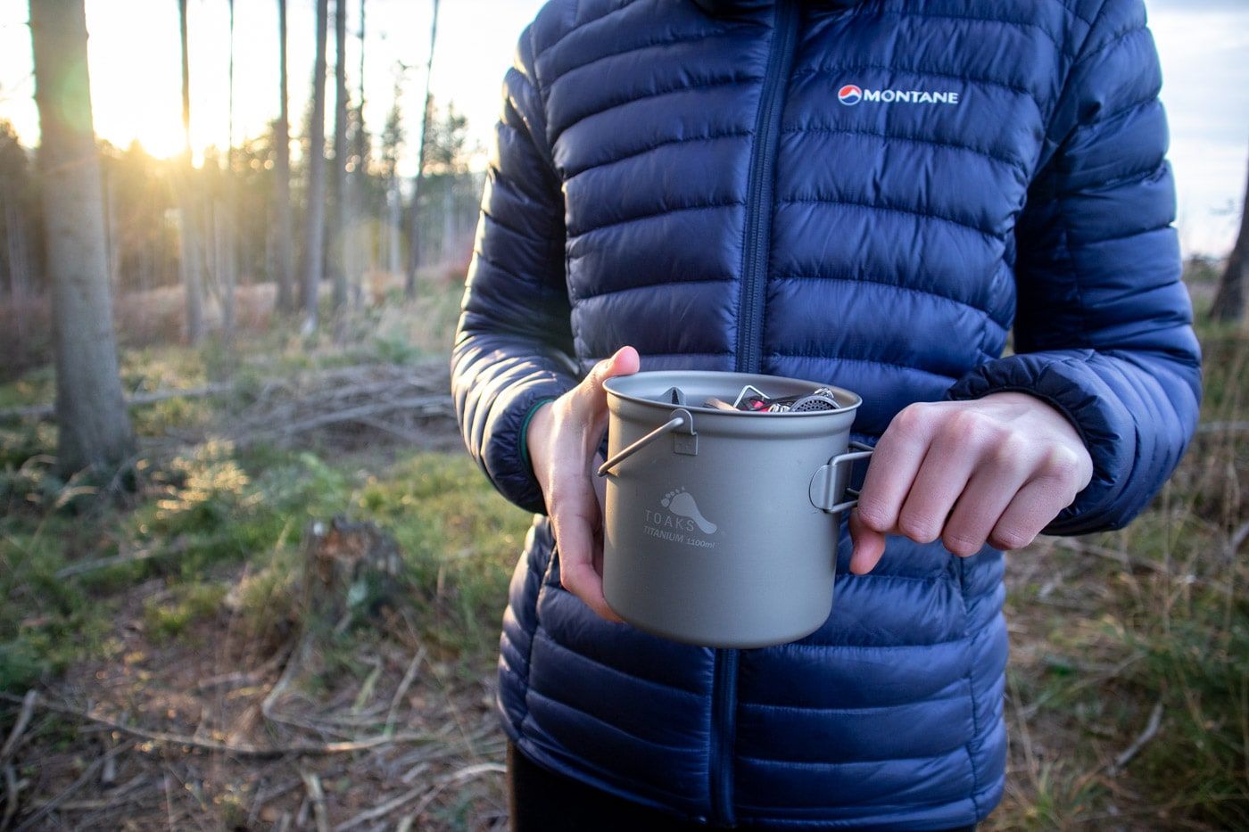 Osoba držící ultralehký hrnec Toaks s obsahem uvnitř.