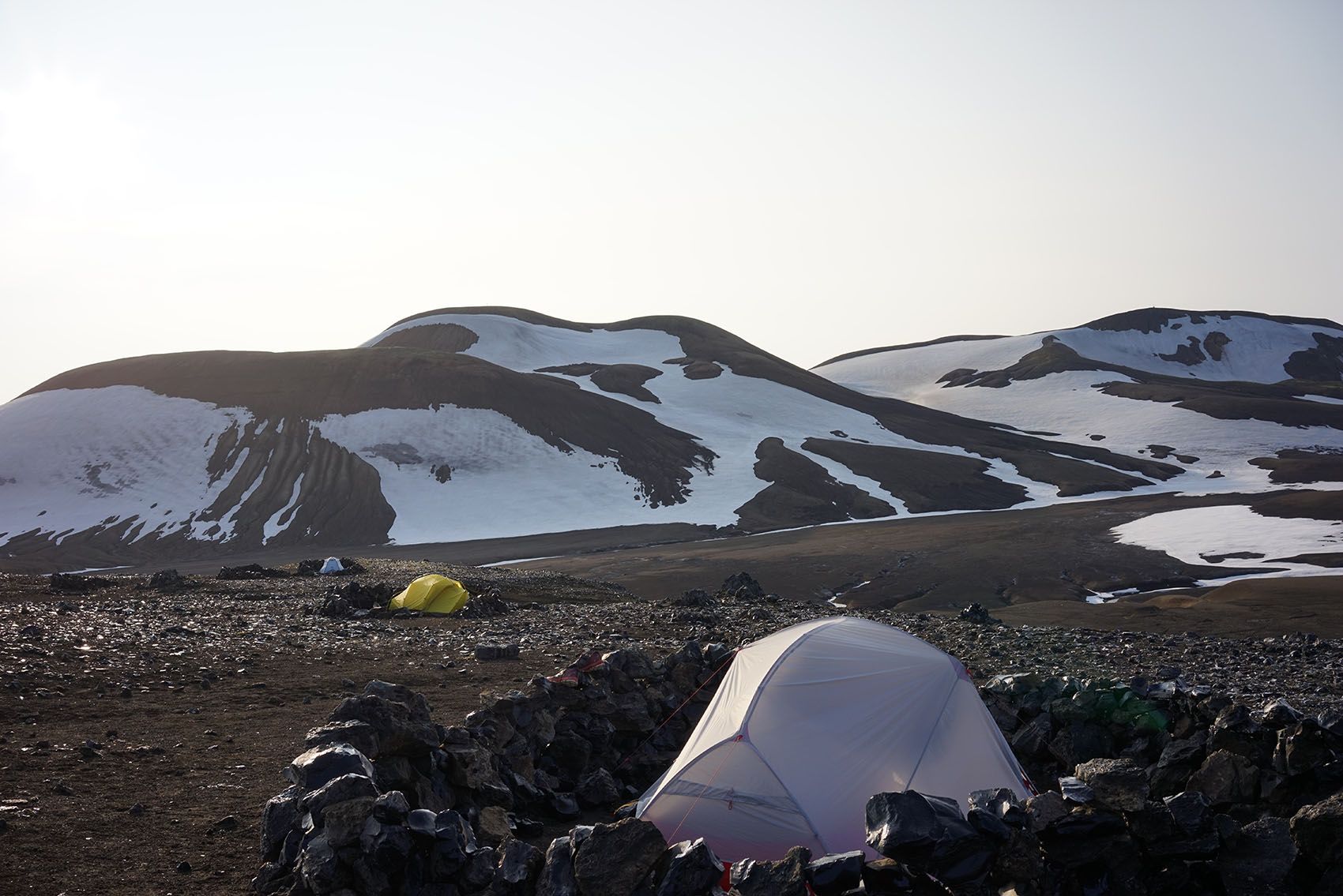 Tři ultralehké stany postavené v zákrytech v pustině.