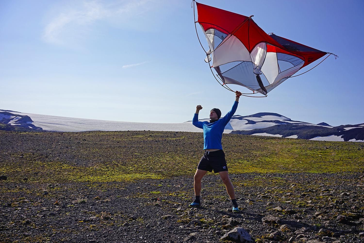 Osoba držící konstrukci ultralehkého stanu v jedné ruce nad sebou.